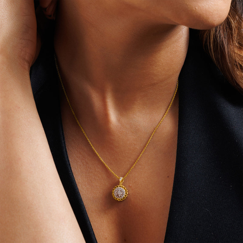 A woman in a black top wears Keemti Jewels' Aurora Cluster Necklet, a gold floral halo with a sparkly round pendant.