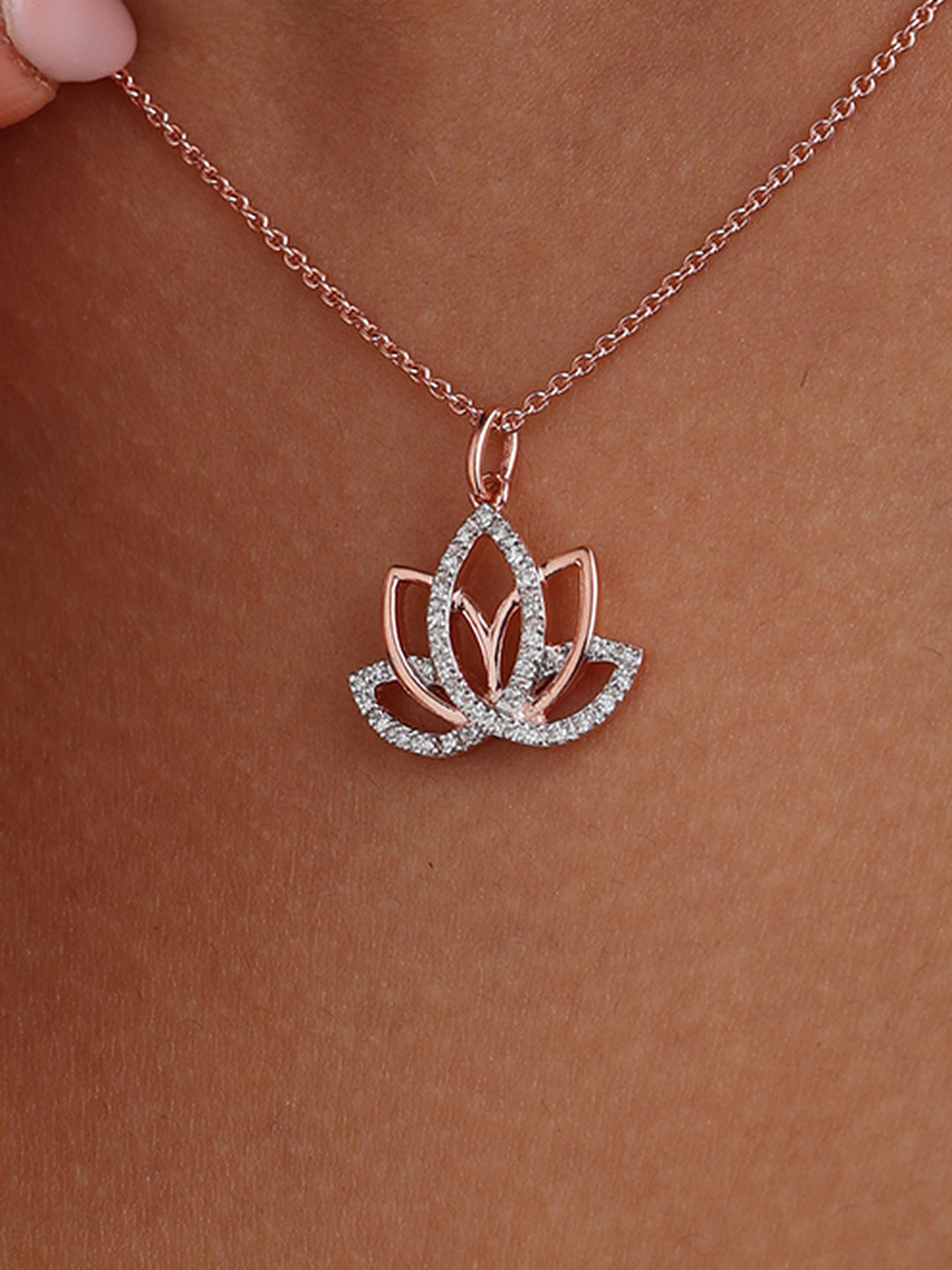 Rose-gold lotus pendant on a delicate chain, resting on the neckline