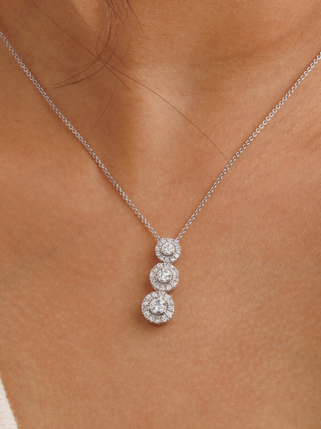 Three halo necklet worn at the collarbone on a fine silver chain.