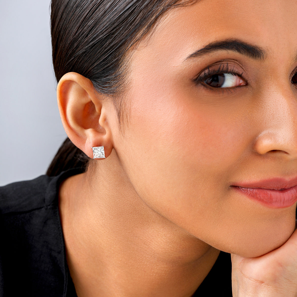 Smiling woman with smooth skin and straight dark hair wears Keemti Jewels PRINCESS Solitaire Stud Earrings.