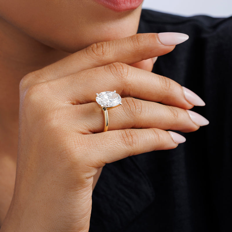 A manicured hand wears the Keemti Jewels MINIMAL Oval Solitaire RING with a gold band on the ring finger.