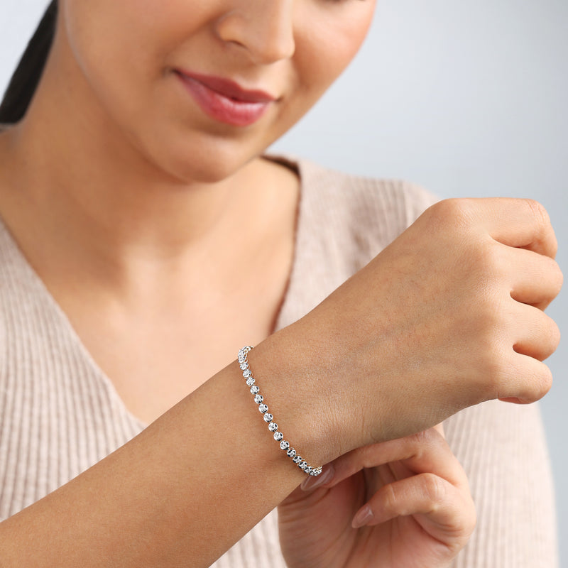 Woman in beige top smiles, admiring the Keemti Jewels Signature Brilliance Diamond Bracelet on her wrist.