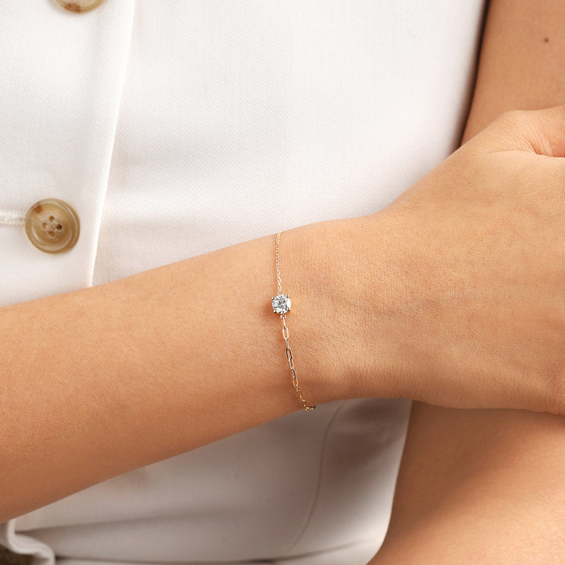 The Keemti Jewels Minimal Round Diamond Bracelet shines on a gold chain, styled with a white sleeveless top.