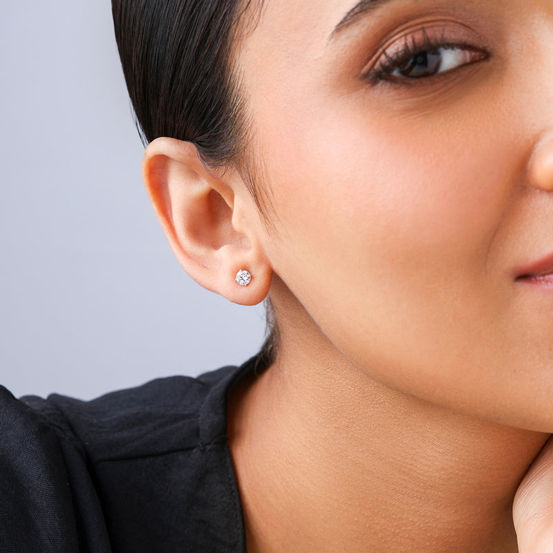 Close-up of a woman wearing Keemti Jewels Timeless Solitaire Stud Earrings in a four-prong setting.