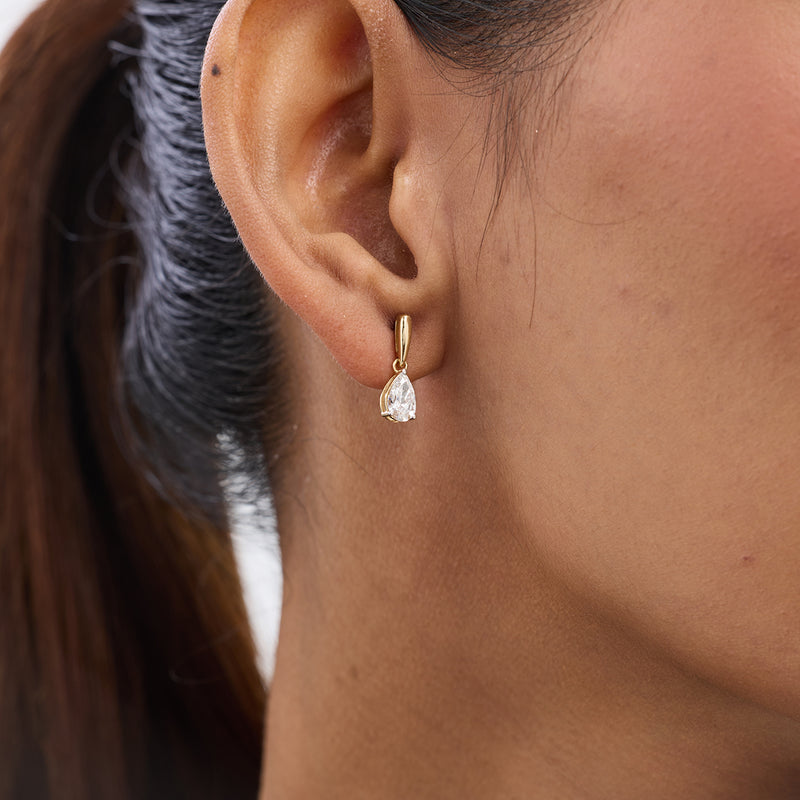 Close-up of a woman's ear wearing Keemti Jewels' Aurora Pear Diamond Drop Earrings with teardrop gems.
