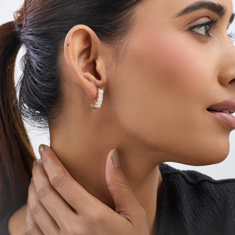 Woman with a ponytail wears Keemti Jewels' Radiant Grid Huggie Diamond Earrings, touching her neck, side view.