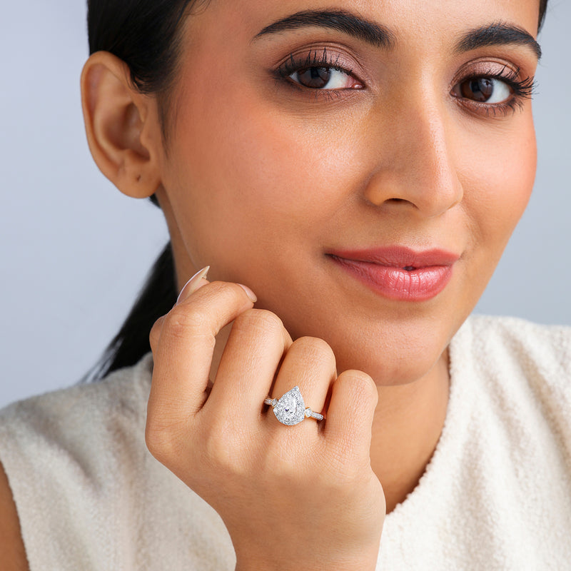 Woman smiling, showcasing Keemti Jewels' Crowned Pear Radiance Diamond Bridal Ring against a light background.