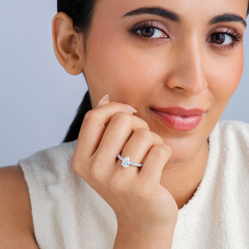 Woman smiles, flaunting Keemti Jewels' Eternal Emerald Solitaire Ring, in a sleeveless white top.
