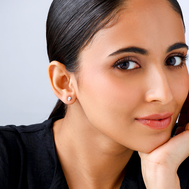 Woman with smooth dark hair smiles softly, wearing Keemti Jewels’ TIMELESS Oval Solitaire Stud Earrings and a black top.